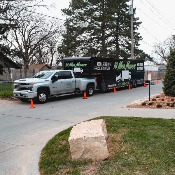 10 Men Movers truck and trailer parked for a long distance moving job, showcasing branded equipment and professional setup for residential or office relocation across Nebraska and beyond.