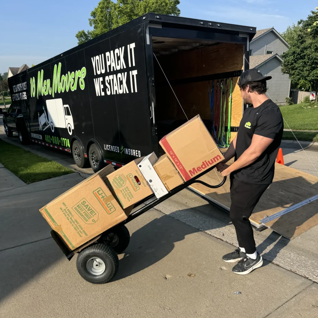 10 Men Movers crew member loading boxes onto a moving trailer for an interstate moving job, showcasing efficient and careful service in a residential neighborhood. Long distance movers Omaha