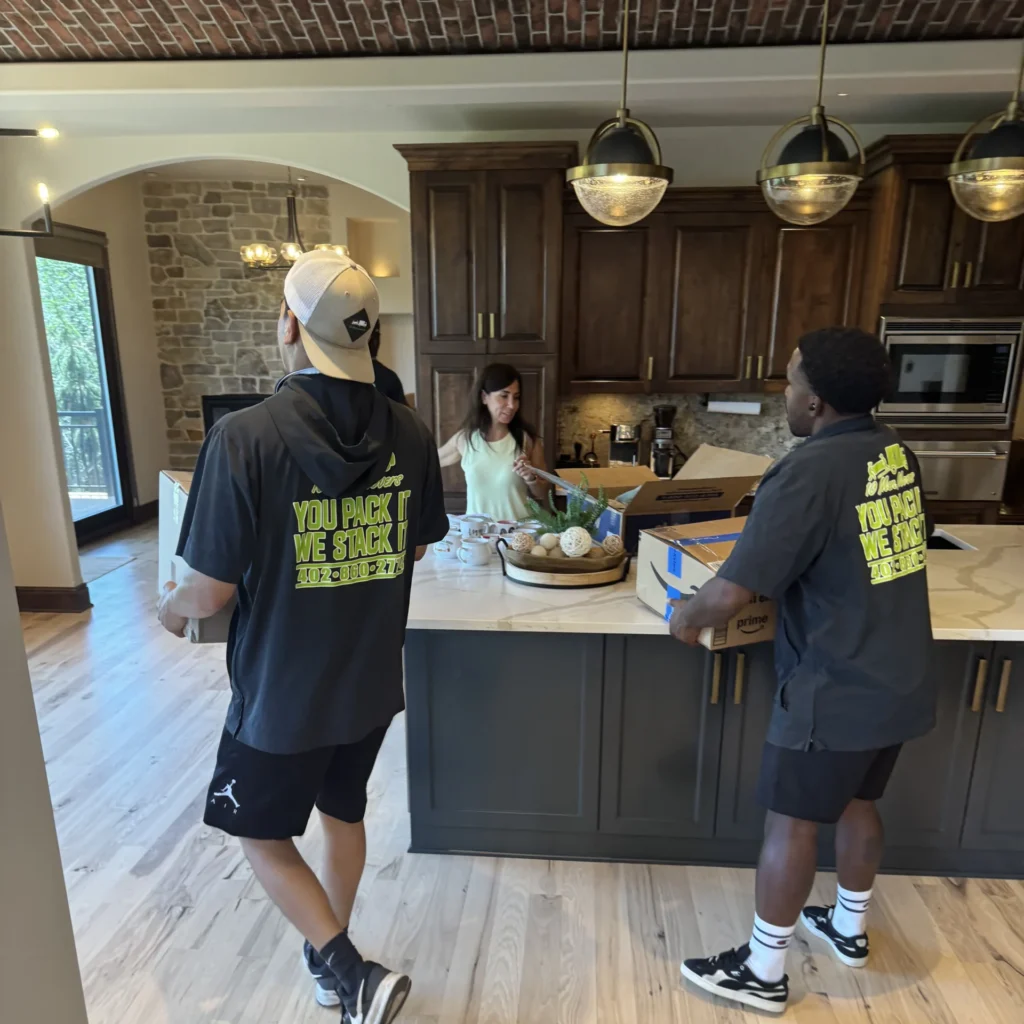 Residential movers assisting a customer with packing in a modern kitchen during a home move. winter moving tips Nebraska
