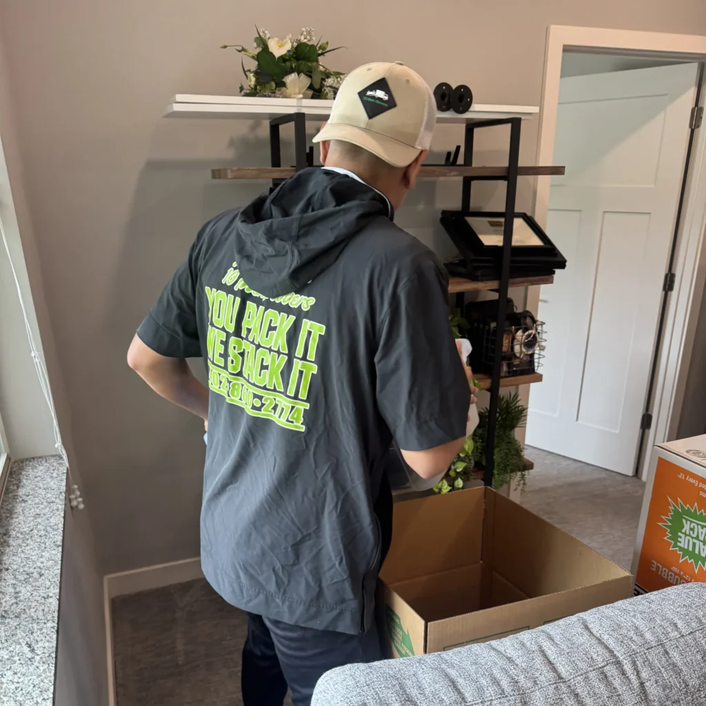 10 Men Movers team member carefully packing boxes during an apartment move, ensuring safe handling of items in a modern living space. Packing Services Omaha