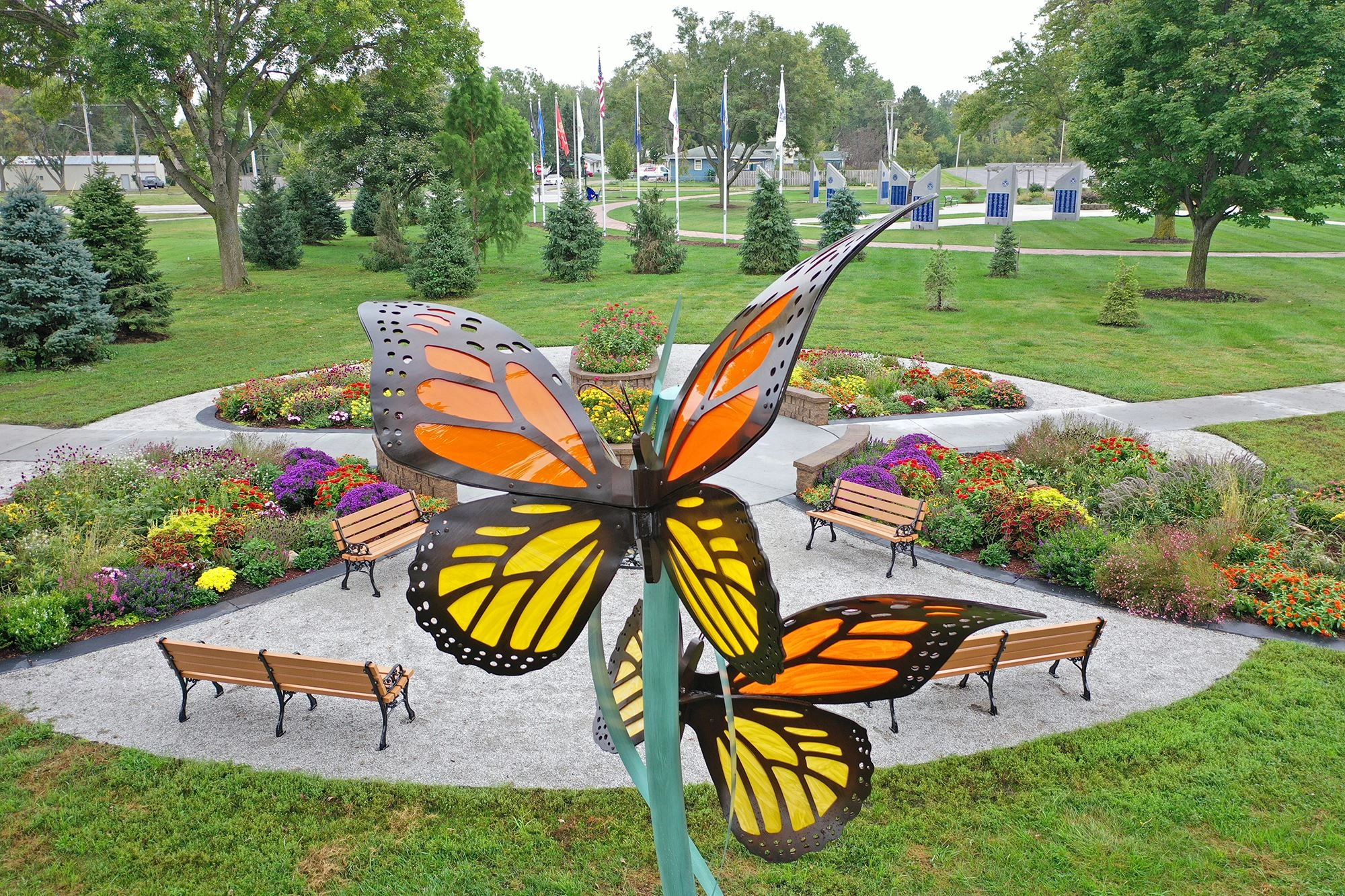 Colorful butterfly sculpture in a landscaped park featuring benches and flower beds, representing community spaces in Omaha, Nebraska.